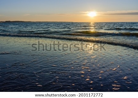 Sunset over the sea. Red and yellow sky in the rays of the sunset. Reflection of sunlight in the sea waves.