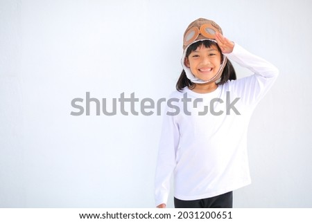 little girl dressed in a cap brown of a pilot. The child dreams of becoming a pilot which increases the development and enhances outside the classroom learning skills concept. on a white background.