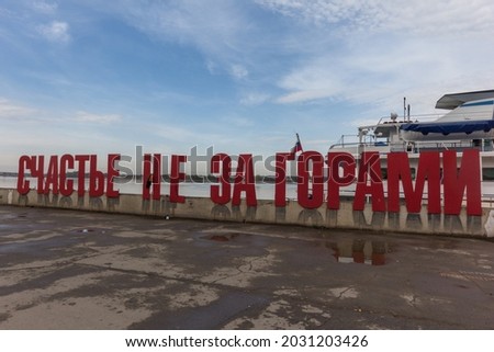 A modern art object on the embankment of the Kama River. A sign in Russian "happiness is not beyond the mountains" against the blue sky. Perm, Russia.
