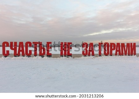 A modern art object on the embankment of the Kama River. A sign in Russian "happiness is not beyond the mountains" on a frosty winter evening. Perm, Russia.