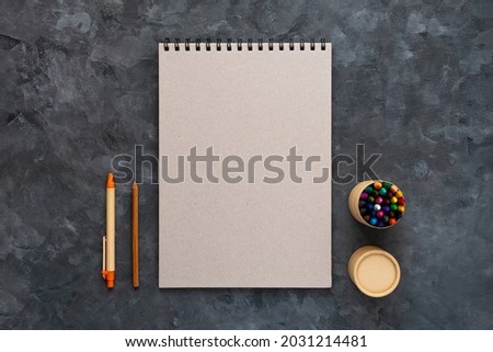 Blank grey cardboard notebook mockup pastel pad dark background flat lay. Minimal work space sketchbook notepad template, eco paper pen. Back to school, stationery, art drawing education e-learning.