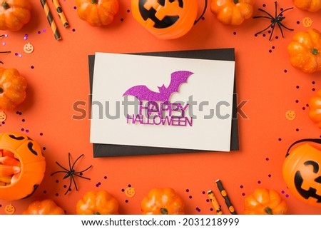 Top view photo of black envelope glitter purple bat and inscription happy halloween on white card violet sequins pumpkin baskets candy corn spiders and straws on isolated orange background