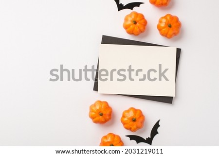 Overhead photo of white card with black frame and halloween decoration pumpkin and bats isolated on the white background