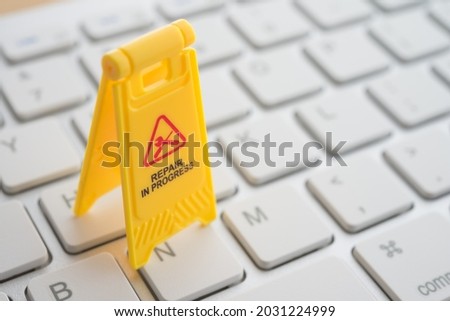Maintenance, repair, update software in computer system from virus or ransomware concept. Close up yellow warning sign "Repair in progress"on white keyboard computer background copy space.