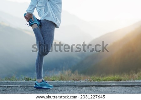 Fit stretch woman stretching quad leg muscle standing getting ready to run jogging outside. Athlete trail running in the mountains on a beautiful morning. Royalty-Free Stock Photo #2031227645