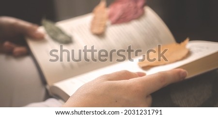 Banner, girl reading old book in cozy autumn days. Book with autumn leaves warm toned background photo