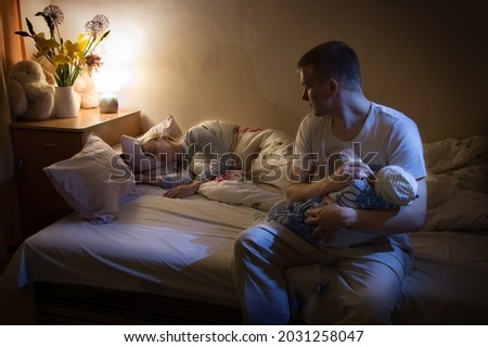 Cute 2 happy married young adult healthy female mum lady worry smile hand hold small new born human male look well health birth heal concept. Little home bedroom pillow mom scene wall view text space Royalty-Free Stock Photo #2031258047