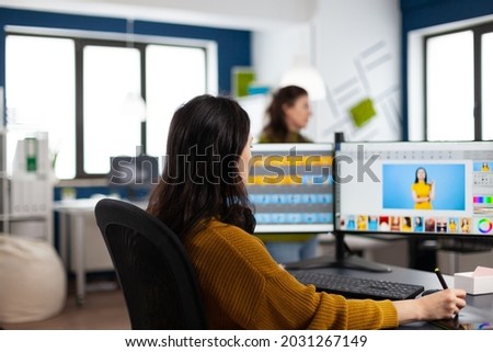Caucasian photographer woman sitting at desk listening music using PC in studio agency office. Designer content creator doing portrait retouching using post production software
