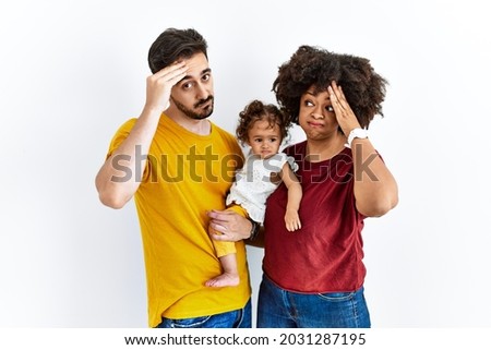 Interracial young family of black mother and hispanic father with daughter worried and stressed about a problem with hand on forehead, nervous and anxious for crisis 