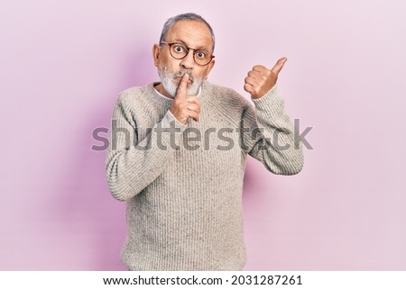 Handsome senior man with beard wearing casual sweater and glasses asking to be quiet with finger on lips pointing with hand to the side. silence and secret concept. 