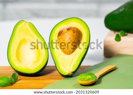 Halves of Ripe Avocado and micro green on wooden board served on table, white background, Healthy oily food, Keto diet, Close up.
