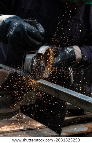 The master saws the metal with a disc grinder. Construction. Sparks. Metal
