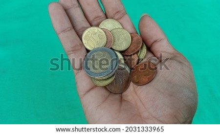 Hand of a man receiving euro coins on a green background.