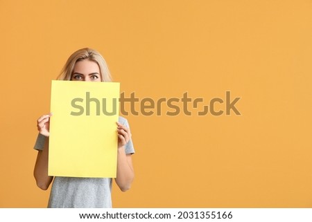 Young woman with blank paper sheet on color background