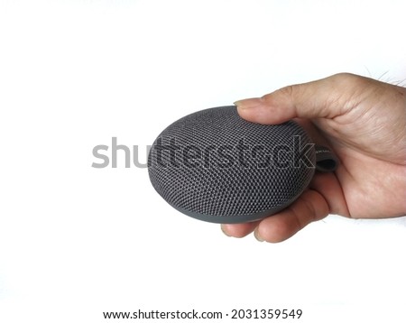 Hand Holding Black grey Mesh Wireless Personal Assistance Smart Speaker Isolated on White Background. Future Technology of Internet Virtual Assistance Speaker is Ready For Smart Home System Device.