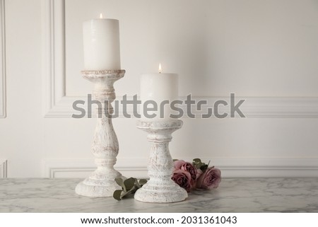 Elegant candlesticks with burning candles and flowers on white marble table Royalty-Free Stock Photo #2031361043