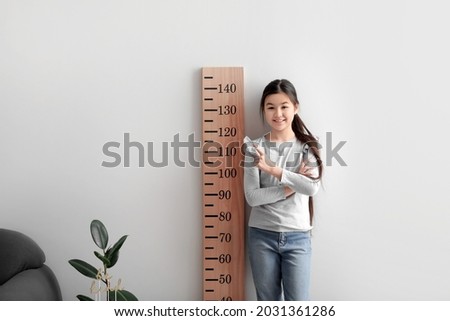 Little girl measuring height at home Royalty-Free Stock Photo #2031361286