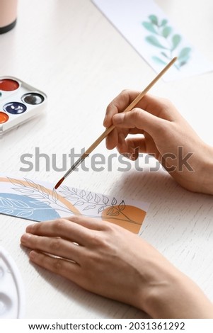 Woman drawing on bookmark at table, closeup