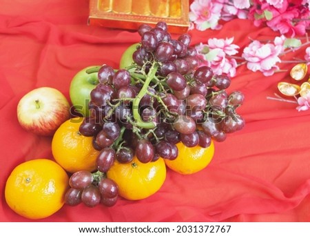 Grapes,Oranges and Apples put on red cloth background,blurry light around