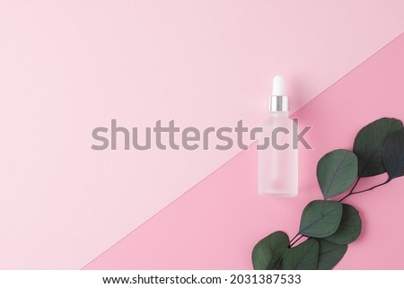Cosmetic bottle with eucalyptus on pink background. Flat lay, copy space