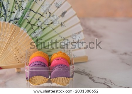 A few delicious macaroon, a famous French dessert with paper hand fan. Selective focus. Blurred background