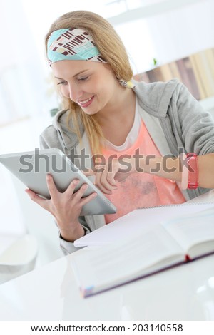 Student girl studying in college library with tablet