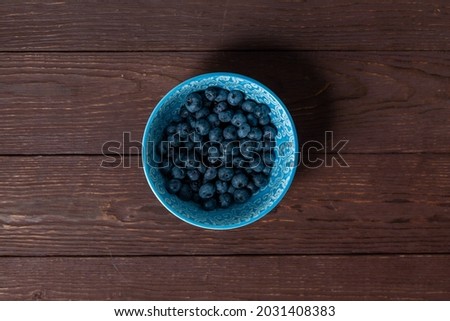 Blueberries in blue bowl on wooden background . High quality photo. Top view.
