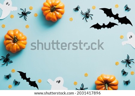 Happy halloween holiday concept. Halloween decorations, bats, ghosts, spiders, pumpkins on blue background. Halloween party greeting card mockup with copy space. Flat lay, top view, overhead.