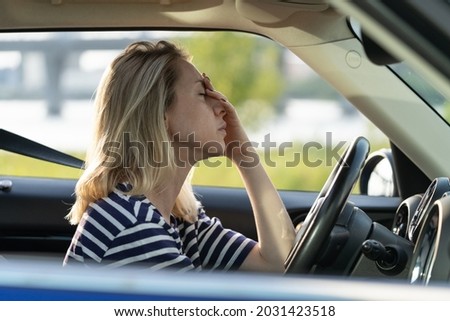 Upset or tired female driver rubbing nose and forehead sitting inside car driving. Middle aged woman suffering from headache, migraineee, panic attack or pms syndrome in vehicle in traffic jam on road Royalty-Free Stock Photo #2031423518