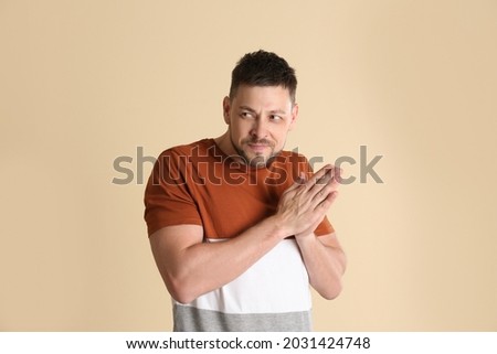 Greedy man rubbing hands on beige background Royalty-Free Stock Photo #2031424748