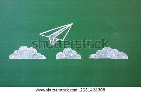 A close-up of a green blackboard and a chalk-drawn airplane taking off above white clouds and a space for copying. Concept-success in business and study Royalty-Free Stock Photo #2031426308