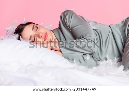 Photo of pretty adorable young woman nightwear lying duvet feather cover face closed eyes isolated pastel pink color background
