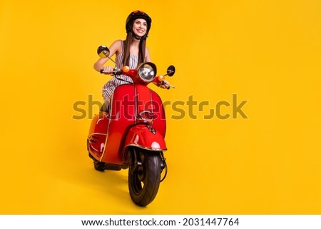 Full length body size photo smiling girl riding motorbike looking blank space isolated vivid yellow color background Royalty-Free Stock Photo #2031447764