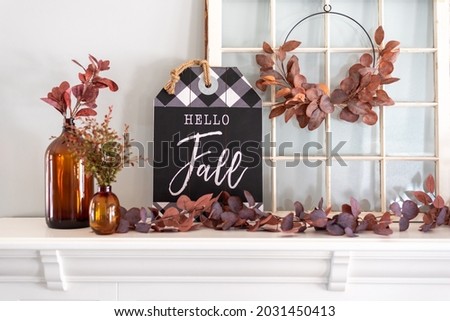 Hello fall sign and amber glass bottles on a white mantel decorated for Fall