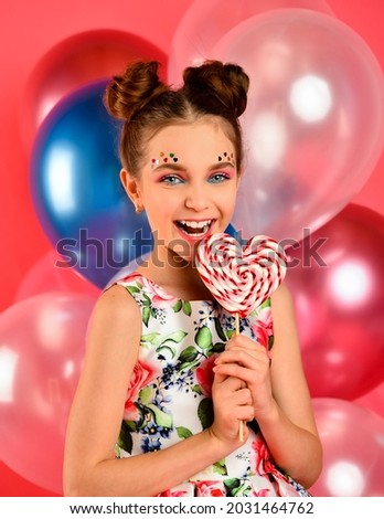 Happy smiling girl with candy and balloons on a pink background, party