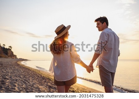 Back rear view young happy lovely couple two friends family man woman in summer clothes hold hands walking stroll together at sunrise over sea beach ocean outdoor exotic seaside in summer day evening Royalty-Free Stock Photo #2031475328