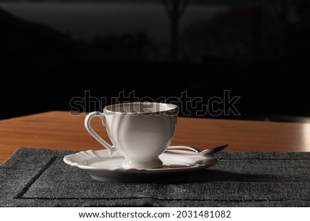 Coffee served on white crockery, with a small spoon over a dark placemat. With space for text.