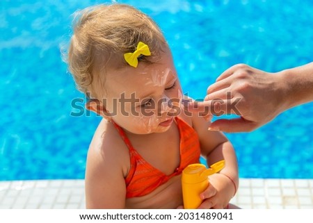 Mother smears sunscreen on the child face. Selective focus. Kid.