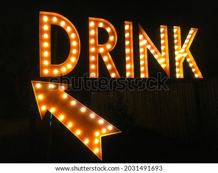 This is a large illuminated "DRINK" sign with an arrow.