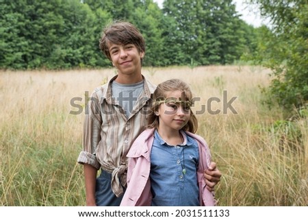 A young man and a girl on a background of dry grass. Portrait of a brother and little sister.