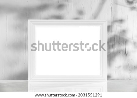 White picture frame on desk and wall with shadows. 