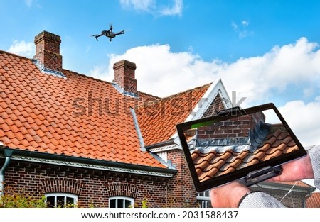 Drone in the air inspecting the roof over the house. Close-up of drone and roof. Royalty-Free Stock Photo #2031588437