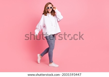 Full length body size view of charming cheerful girl walking touching specs isolated over pink pastel color background