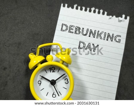 Education concept.Text DEBUNKING DAY writing on notepaper with alarm clock on black background. Royalty-Free Stock Photo #2031630131