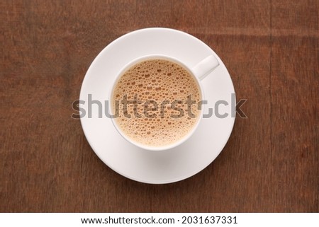 Top view of Indian Masala Chai or traditional beverage with tea, milk and spices in white cup Kerala India Sri Lanka. organic ayurvedic or herbal drink India, good in winter for immunity boosting. Royalty-Free Stock Photo #2031637331