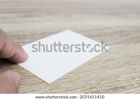 Hand holding white note on wooden table. 