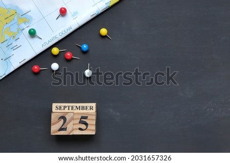 September 25th. Hello September, Cube wooden calendar showing date on 25 September, Wooden calendar with colorful thumbtack on map.