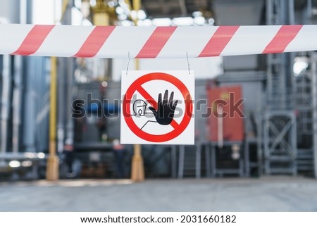 A poster of the Forbidden zone on a red and white ribbon fencing the passage against the background of the pipes of the power plant. Unauthorized persons are not allowed to enter the factory