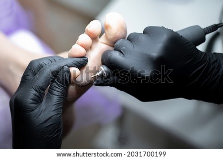 Beauty salon, a master in black gloves makes a hardware pedicure to the client. The concept of health and care procedure, healthy lifestyle, pedicure master does his job, service and customer service.
