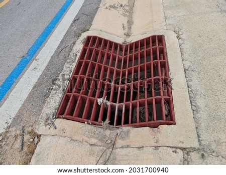 red brown steel grating that is curved down to blend in with the rainwater drainage ditch 